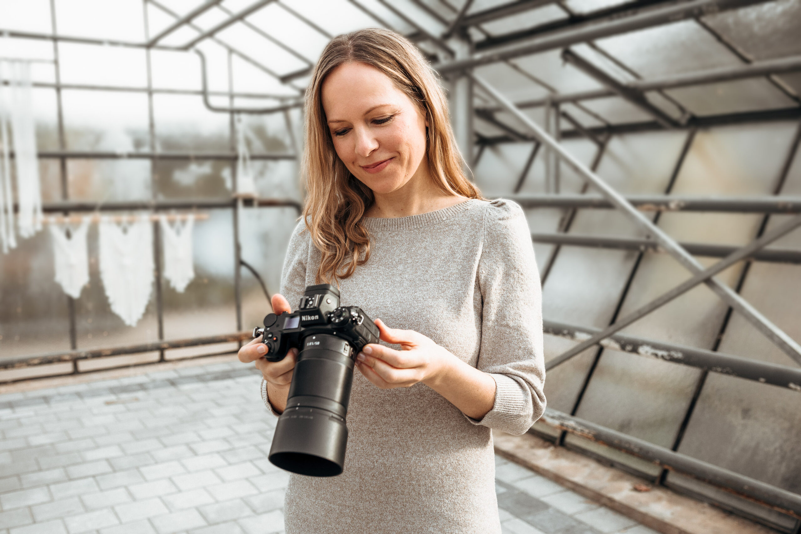 Fotografin schaut auf das Display ihrer Kamera und lächelt.